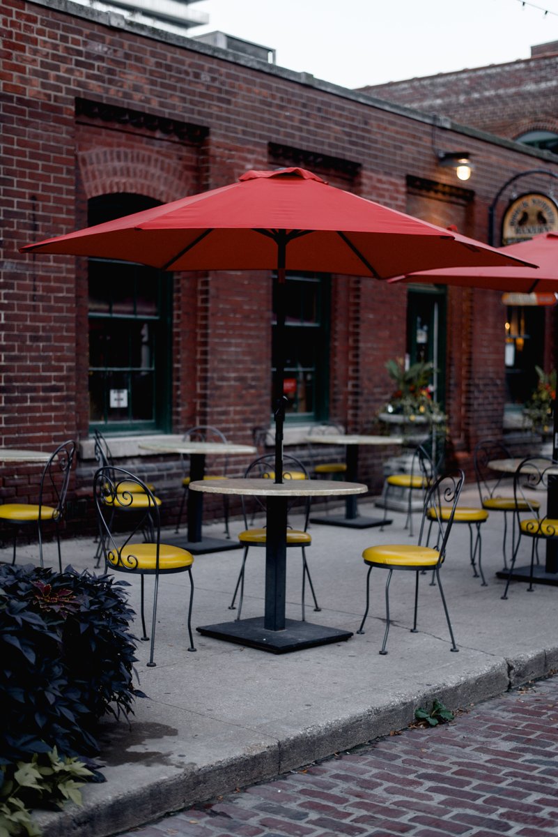 Outdoor cafe seating beside a brick storefront