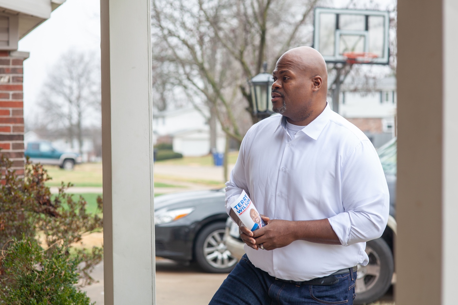 Terry Wilson standing on a front porch holding campaign literature